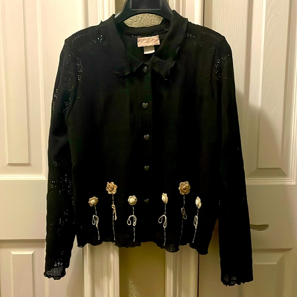 Black, loose knit sweater with heart buttons and small, crocheted flowers.